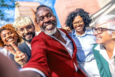 Άνθρωποι διαφορετικής ηλικίας, φυλής και φύλου χαμογελούν έξω από ένα κτίριο